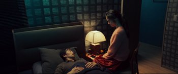 Movie still from “Decision to Leave” (2022), directed by Park Chan-wook – A man laying in a bed next to a woman; Medium shot, High angle