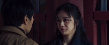 Movie still from “Decision to Leave” (2022), directed by Park Chan-wook – A young asian woman with long black hair looking to her left; Close Up shot, Over the shoulder angle