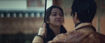 Movie still from “Decision to Leave” (2022), directed by Park Chan-wook – A woman holding an umbrella over her head; Close Up shot, Over the shoulder angle
