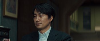 Movie still from “Decision to Leave” (2022), directed by Park Chan-wook – A person wearing a suit and tie; Close Up shot, Over the shoulder angle