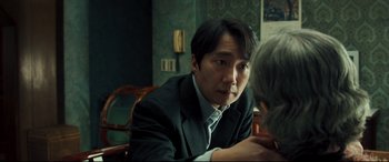 Movie still from “Decision to Leave” (2022), directed by Park Chan-wook – A man sitting at a table in front of another man; Close Up shot, Over the shoulder angle