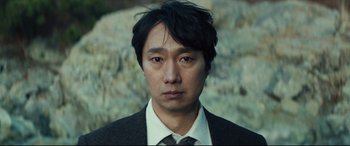 Movie still from “Decision to Leave” (2022), directed by Park Chan-wook – A person wearing a suit and tie; Close Up shot, Over the shoulder angle