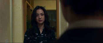 Movie still from “Decision to Leave” (2022), directed by Park Chan-wook – A woman standing in front of a mirror looking at the camera; Close Up shot, Over the shoulder angle