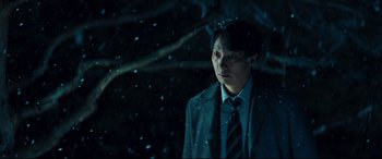 Movie still from “Decision to Leave” (2022), directed by Park Chan-wook – A man wearing a suit and tie standing in the snow; Medium shot, Low angle