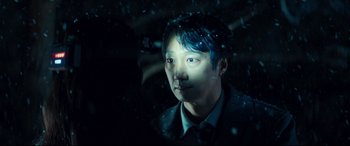 Movie still from “Decision to Leave” (2022), directed by Park Chan-wook – A man with blue hair is looking at the camera through a window; Close Up shot, Over the shoulder angle