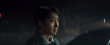 Movie still from “Decision to Leave” (2022), directed by Park Chan-wook – A person wearing a suit and tie; Close Up shot, Over the shoulder angle