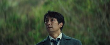 Movie still from “Decision to Leave” (2022), directed by Park Chan-wook – A person wearing a suit and tie; Close Up shot, Low angle