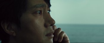 Movie still from “Decision to Leave” (2022), directed by Park Chan-wook – A person with his hand on his chin; Close Up shot, Low angle