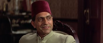 Movie still from “Gandhi” (1982), directed by Richard Attenborough – A person sitting in a chair wearing a fez; Close Up shot, Low angle