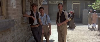 Movie still from “Gandhi” (1982), directed by Richard Attenborough – A group of men standing next to each other on a sidewalk; Medium shot, Low angle