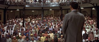 Movie still from “Gandhi” (1982), directed by Richard Attenborough – A large group of people are sitting in a room; Wide shot, High angle