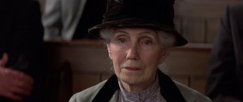 Movie still from “Gandhi” (1982), directed by Richard Attenborough – An older woman wearing a hat and a jacket; Close Up shot, Over the shoulder angle