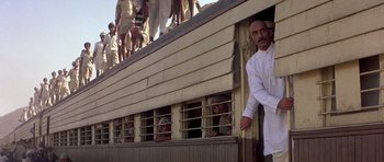 Movie still from “Gandhi” (1982), directed by Richard Attenborough – A group of people standing on the side of a building; Medium shot, Low angle