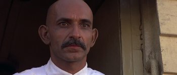 Movie still from “Gandhi” (1982), directed by Richard Attenborough – A man with a bald head wearing a white shirt; Close Up shot, Low angle