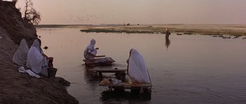Movie still from “Gandhi” (1982), directed by Richard Attenborough – Two people sitting on a raft in the middle of a river; Extreme Wide shot, High angle