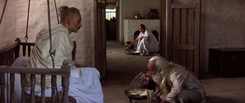 Movie still from “Gandhi” (1982), directed by Richard Attenborough – A group of men sitting around eating food; Wide shot, High angle