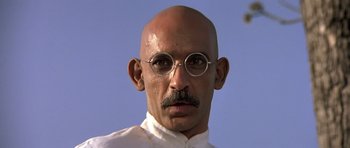 Movie still from “Gandhi” (1982), directed by Richard Attenborough – A bald man with glasses and a bald head; Close Up shot, Low angle