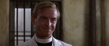 Movie still from “Gandhi” (1982), directed by Richard Attenborough – A man in a priest's outfit smiling for the camera; Close Up shot, Low angle