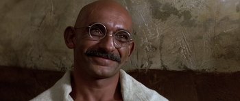 Movie still from “Gandhi” (1982), directed by Richard Attenborough – A bald man with glasses and a mustache wearing a towel; Close Up shot, Over the shoulder angle