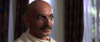 Movie still from “Gandhi” (1982), directed by Richard Attenborough – An old man with a mustache wearing round glasses; Close Up shot, Over the shoulder angle