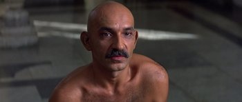 Movie still from “Gandhi” (1982), directed by Richard Attenborough – A bald man with a mustache is posing for a picture; Close Up shot, High angle