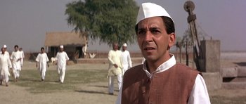 Movie still from “Gandhi” (1982), directed by Richard Attenborough – A man wearing a white hat standing next to two other men; Close Up shot, Low angle