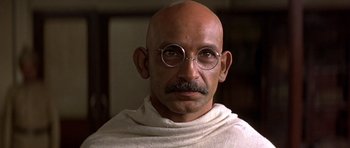 Movie still from “Gandhi” (1982), directed by Richard Attenborough – An old man with a bald head wearing round glasses; Close Up shot, Low angle