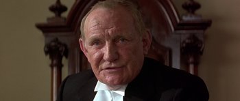 Movie still from “Gandhi” (1982), directed by Richard Attenborough – An older man wearing a suit and white tie; Close Up shot, Low angle