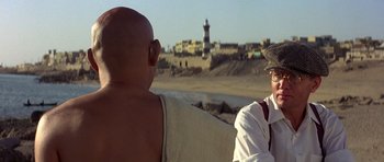 Movie still from “Gandhi” (1982), directed by Richard Attenborough – Two men sitting on a bench looking out at the beach; Close Up shot, Over the shoulder angle