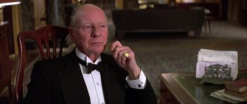 Movie still from “Gandhi” (1982), directed by Richard Attenborough – An older man in a tuxedo holding a piece of gold; Close Up shot, Low angle