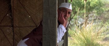 Movie still from “Gandhi” (1982), directed by Richard Attenborough – A man leaning up against a wooden pole; Close Up shot, Low angle