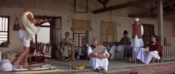 Movie still from “Gandhi” (1982), directed by Richard Attenborough – A group of men sitting on a porch; Wide shot, Low angle
