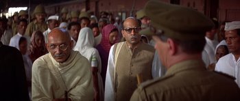 Movie still from “Gandhi” (1982), directed by Richard Attenborough – A group of people standing next to each other; Medium shot, Over the shoulder angle