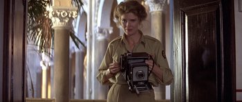 Movie still from “Gandhi” (1982), directed by Richard Attenborough – A woman holding an old fashioned camera in front of an archway; Medium shot, Low angle