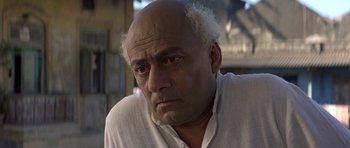 Movie still from “Gandhi” (1982), directed by Richard Attenborough – An older man with a bald head looking sad; Close Up shot, High angle