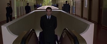 Movie still from “Gattaca” (1997), directed by Andrew Niccol – A man in a suit standing on some escalators; Medium shot, Low angle