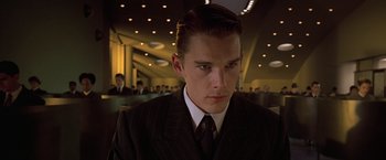 Movie still from “Gattaca” (1997), directed by Andrew Niccol – A man in a suit and tie in front of a group of people; Close Up shot, Low angle
