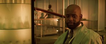 Movie still from “Gattaca” (1997), directed by Andrew Niccol – A man in a green shirt and tie in front of a railing; Close Up shot, Low angle