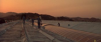Movie still from “Gattaca” (1997), directed by Andrew Niccol – A group of people riding skateboards on top of a ramp; Extreme Wide shot, Low angle