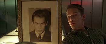 Movie still from “Gattaca” (1997), directed by Andrew Niccol – A man standing in front of a picture of himself; Close Up shot, Low angle