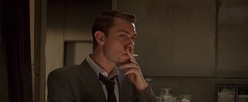 Movie still from “Gattaca” (1997), directed by Andrew Niccol – A man in a suit and tie smoking a cigarette; Close Up shot, Low angle