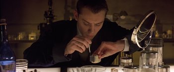 Movie still from “Gattaca” (1997), directed by Andrew Niccol – A man in a black suit is eating a dessert; Close Up shot, Low angle