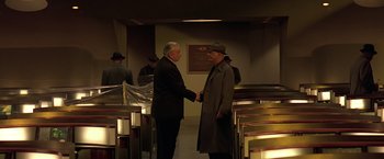 Movie still from “Gattaca” (1997), directed by Andrew Niccol – Two older men shaking hands in a room; Wide shot, High angle