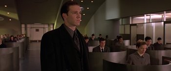 Movie still from “Gattaca” (1997), directed by Andrew Niccol – A man in a suit and tie standing in front of a group of people; Medium shot, Low angle