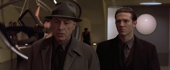 Movie still from “Gattaca” (1997), directed by Andrew Niccol – A man in a hat and a man in a suit; Close Up shot, Low angle