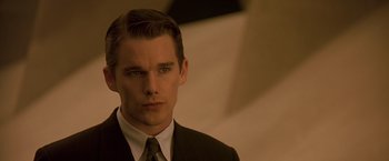 Movie still from “Gattaca” (1997), directed by Andrew Niccol – A man in a suit and tie looking at the camera; Close Up shot, Over the shoulder angle