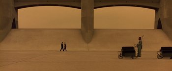 Movie still from “Gattaca” (1997), directed by Andrew Niccol – Two people walking under a large concrete structure; Extreme Wide shot, High angle