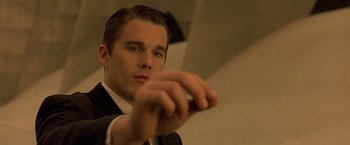 Movie still from “Gattaca” (1997), directed by Andrew Niccol – A man in a black suit and white shirt holding his hand out; Close Up shot, Low angle