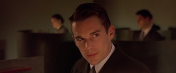 Movie still from “Gattaca” (1997), directed by Andrew Niccol – A man wearing a suit and tie in front of a computer screen; Close Up shot, Low angle