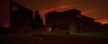 Movie still from “Gattaca” (1997), directed by Andrew Niccol – Cars parked in front of a building at night time; Extreme Wide shot, Low angle